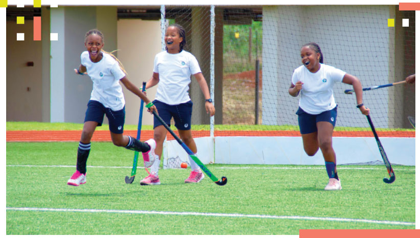 Students smiling on the field as they play a sport